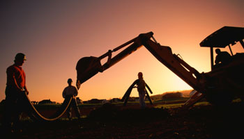 construction workers and equipment at sunset